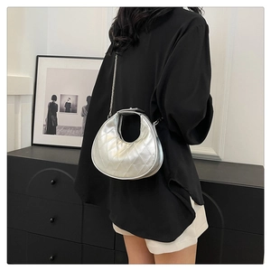 Détail du sac demi-lune argenté avec coutures matelassées porté par un mannequin