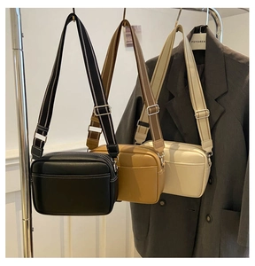 Three minimalist camera-style crossbody bags in black, brown, and white with wide straps