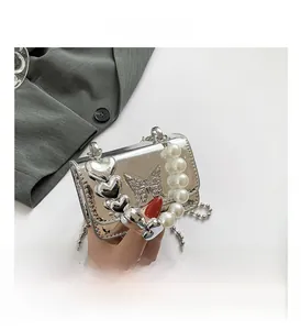 Detail of silver mirror PU crossbody bag with butterfly relief and pearl heart handle