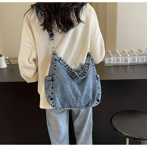 Detail van de blauwe gewassen denim halve maan tas met zijzakken en brede riem