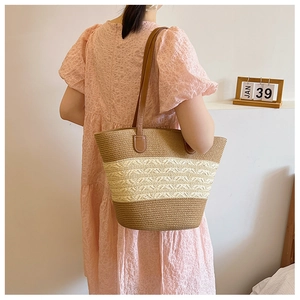 Chic woven tote bag with brown leather straps shown in a minimalist fashion scene