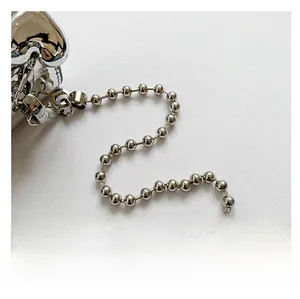 Close-up of shiny silver PU crossbody bag with metallic ball chain shoulder strap