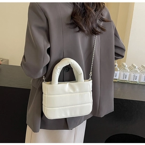 Detail of white quilted PU crossbody bag with puffy texture and metal bead chain strap