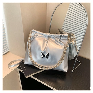 Silver PU leather shoulder bag with butterfly motif and pleated design in soft lighting