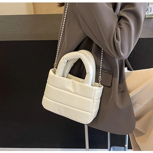 Detail of quilted ivory PU leather handbag featuring soft padded handle and silver ball chain
