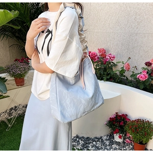 Detail of light blue pleated PU crossbody bag featuring pink drawstring and ruffled straps