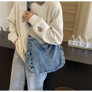 Detail van blauwe gewassen denim canvas crossbodytas met metalen haken en brede riem