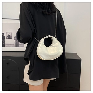 Gros plan détaillé du sac bandoulière blanc en demi-lune avec matelassage losange et chaîne argent