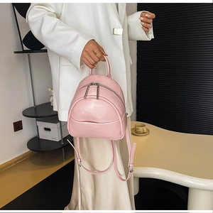 Chic pink mini PU leather backpack held by model in a modern minimalist setting