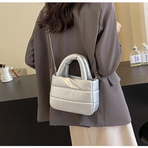 Detail of silver quilted metallic handbag with chain strap shown on a model's back