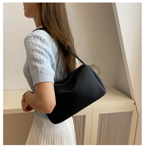 Detail view of black lychee grain PU leather shoulder bag worn by model in light studio