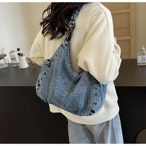 Detail van blauwe denim hobo tas met verstelbare riem getoond op een model