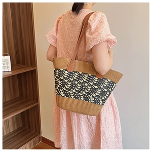 Detail of woven tote bag with geometric patterns and leather shoulder strap on a model