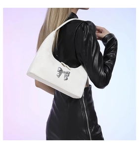 Detail of white PU leather hobo bag with metallic bow, worn by model in black jacket