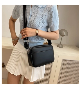 Close-up of black PU leather crossbody bag featuring a striped fabric wide shoulder strap