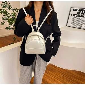 Minimalist white PU leather mini backpack shown on model in a stylish indoor setting