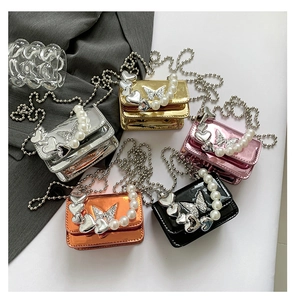 Detail of mini crossbody bags featuring pearl handles and diamond butterfly ornaments