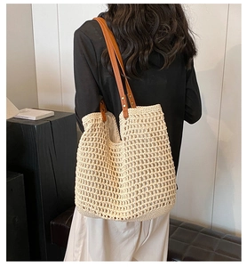 Close-up of woven tote bag featuring mesh texture and brown leather shoulder straps