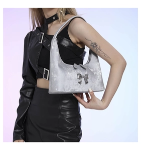 Detail of silver PU leather handbag with a metallic bow ornament and pearlescent texture
