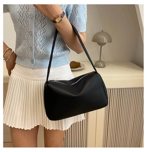 Detail shot of black pebbled leather texture on minimalist chic underarm shoulder bag