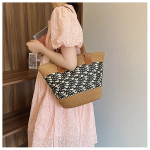 Close-up of a woven tote bag with brown leather details shown in a lifestyle setting