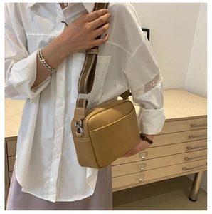 Detail of khaki PU leather camera bag with striped woven strap shown on model shoulder