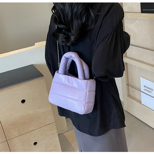 Detailed close-up of quilted lavender puffy bag with metallic chain and soft texture