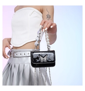 Detail of PU leather bag with butterfly metal piece, pearl handle and heart chain strap