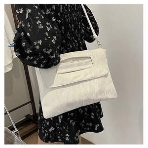 Detail of white PU crossbody bag featuring unique crinkle texture and gold metal hardware