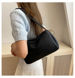 Chic black PU shoulder bag with pebble texture styled on a model in a cozy indoor setting