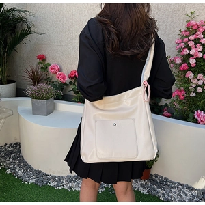 Macro detail of creamy PU leather tote bag featuring a large minimalist square front pocket