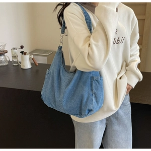 Detail van blauwe denim hobo tas met contrasterende stiksels en zilveren metalen haak