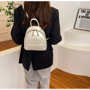 Minimalist creamy white PU leather mini backpack shown on model in a modern interior