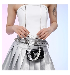 Detail of a black patent leather crossbody bag with a silver butterfly and pearl handle