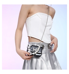 Detail of black patent leather mini square bag with crystal butterfly buckle and pearl handle