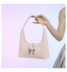 Detailed close-up of pink faux leather shoulder bag with a silver metal bow accent