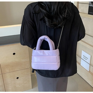 Detailed view of lavender quilted crossbody bag with silver bead chain strap on model