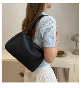 Detail view of black lychee grain PU leather shoulder bag on model for daily use