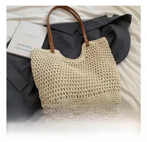 Close-up of cream woven tote bag with large mesh pattern and brown leather handles
