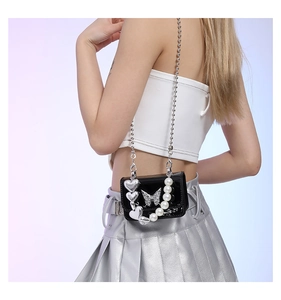 Detail of black patent leather mini crossbody bag with pearl and butterfly charms
