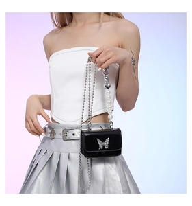 Detail of black patent leather crossbody bag with silver butterfly and pearl heart chain