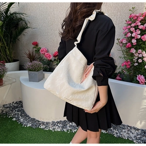 Detail of white PU shoulder bag with ruffles and pink drawstring in an outdoor setting