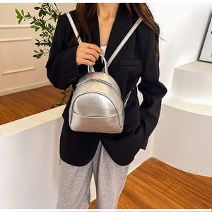 Detailed view of the metallic silver PU leather mini backpack on a person for scale