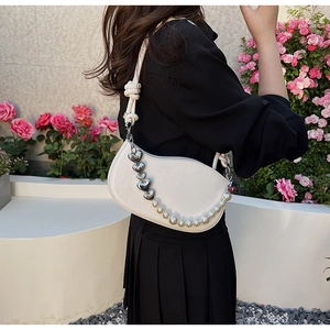 Détail du sac demi-lune blanc avec chaîne en cœur et breloques en perles