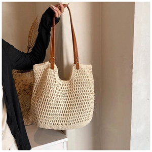 Close-up of beige crochet tote bag with brown leather straps and vintage gold rivets