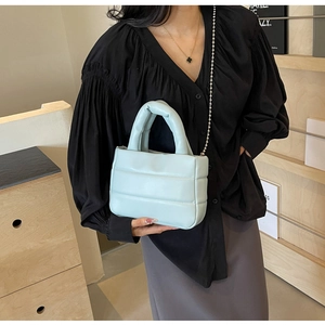 Close-up of light blue quilted PU leather bag with metal chain strap and top handle