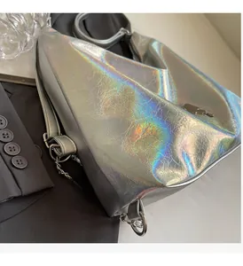 Detail of holographic silver handbag with metallic texture and round metal handle ring