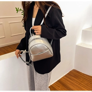 Silver mini PU leather backpack with metallic finish shown on model in black suit