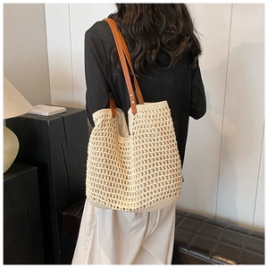 Detailed view of beige woven tote bag with brown leather straps worn by a model