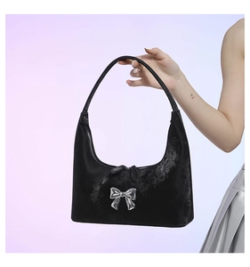 Detail shot of the glossy black velvet baguette bag with a silver metallic bow accent